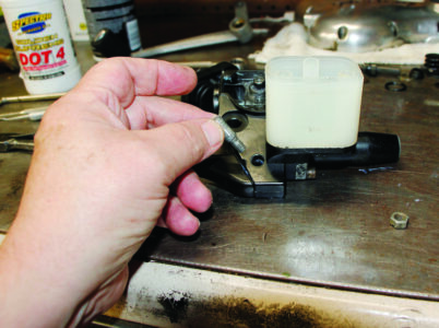 hand and two fingers holding gray pin with threads at the bottom ready to insert…